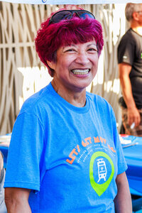 Photo: Event volunteer smiles, wearing a commemorative tee shirt.